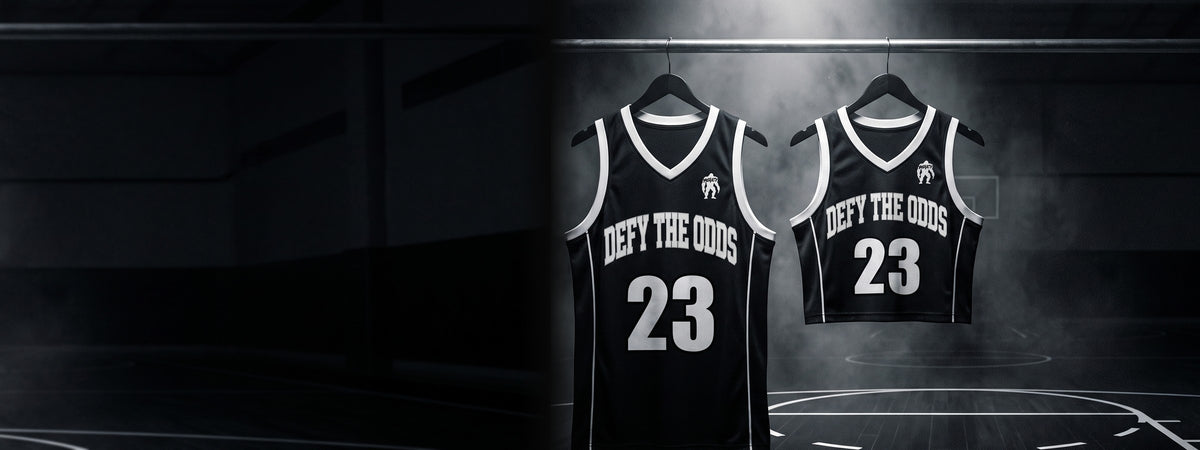 Defy The Odds men's full-length and women's cropped jerseys hanging under a spotlight